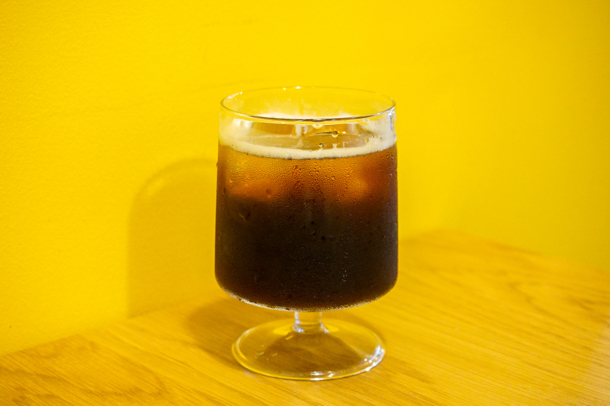 黄色い壁に生える、アイスコーヒー